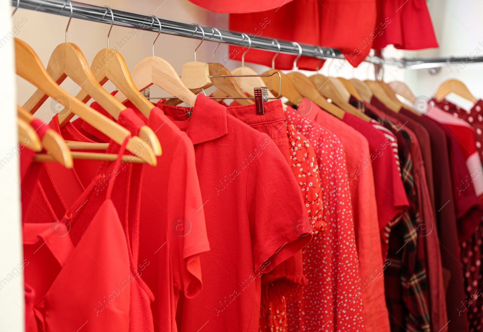 Photo of Different red clothes on hangers in wardrobe. Fashion blogger