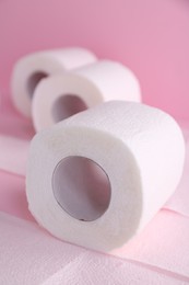 Photo of Soft toilet paper rolls on pink background, closeup