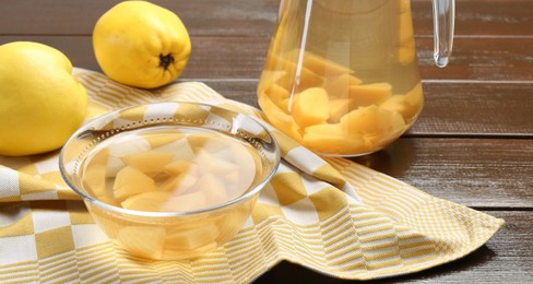 Photo of Delicious quince drink and fresh fruits on wooden table, closeup