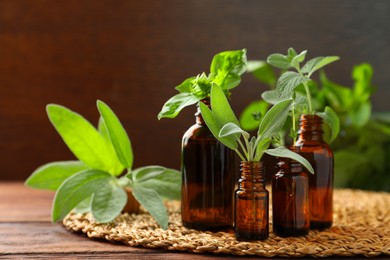 Bottles of essential oils and fresh herbs on wooden table, space for text