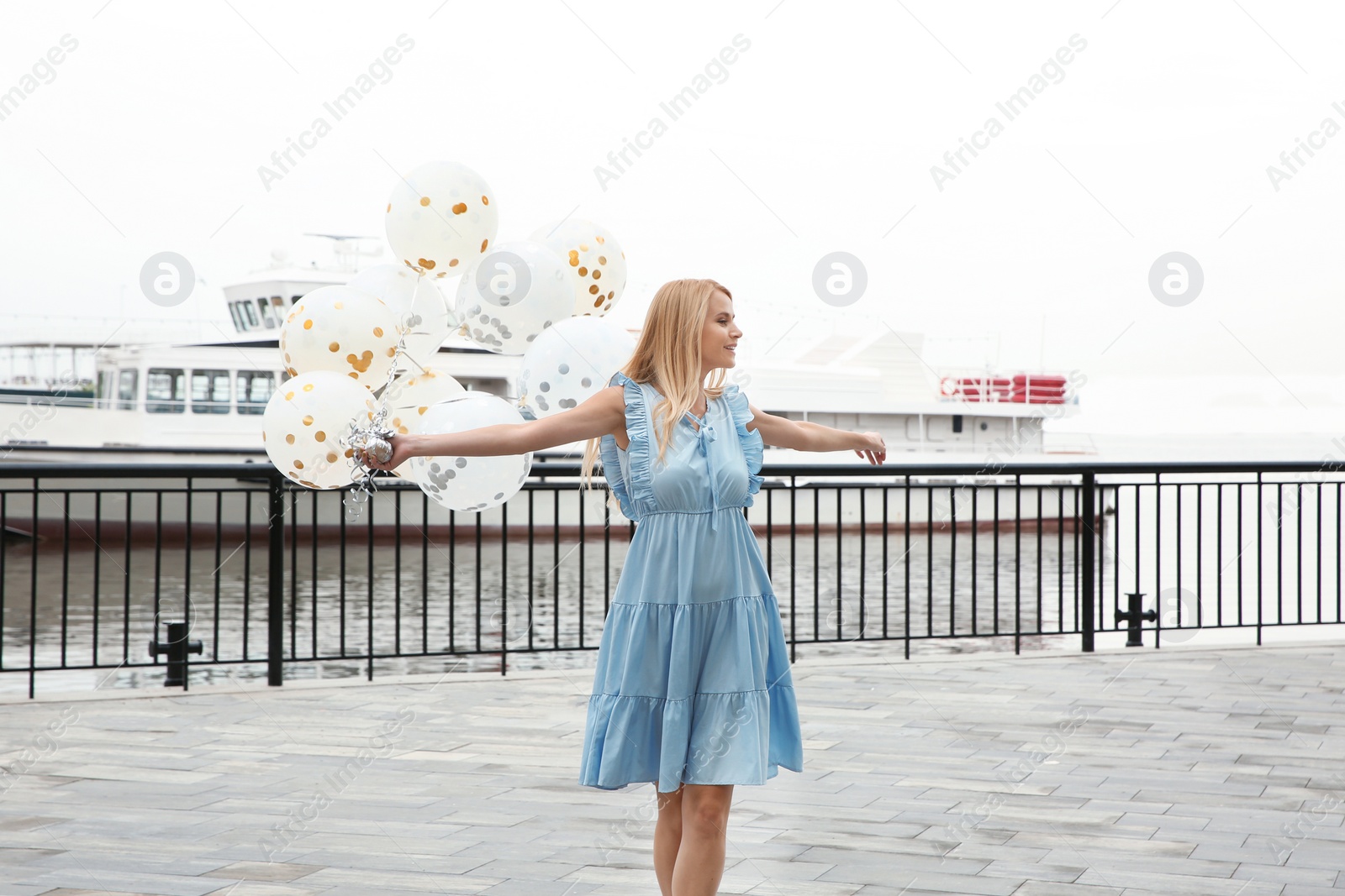 Photo of Beautiful young woman with bunch of balloons outdoors