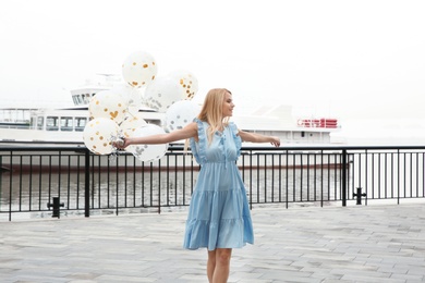 Photo of Beautiful young woman with bunch of balloons outdoors