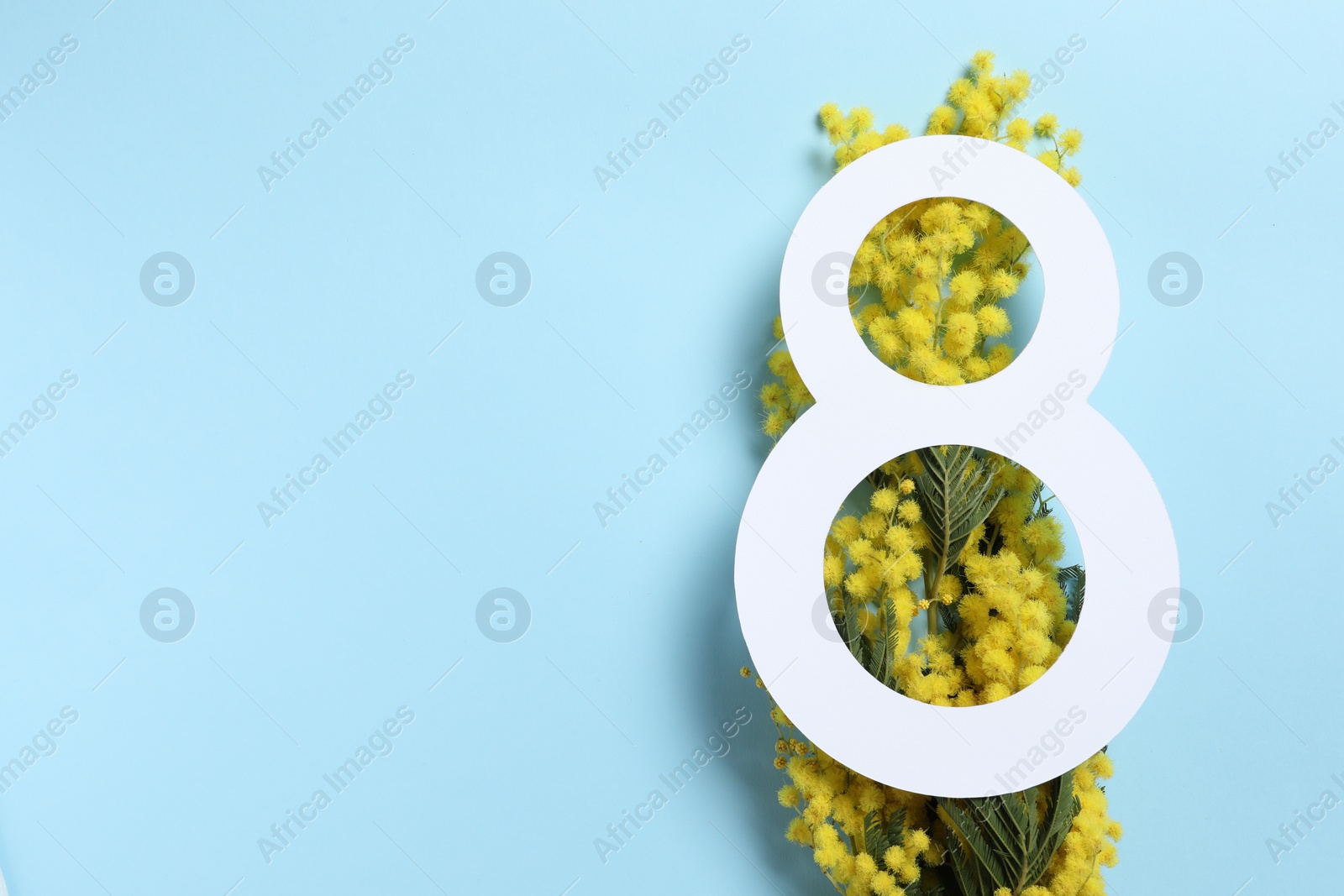 Photo of 8 March greeting card design with yellow mimosa flowers on light blue background, top view. Happy International Women's Day
