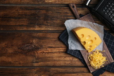 Photo of Tasty grated cheese on wooden table, flat lay. Space for text