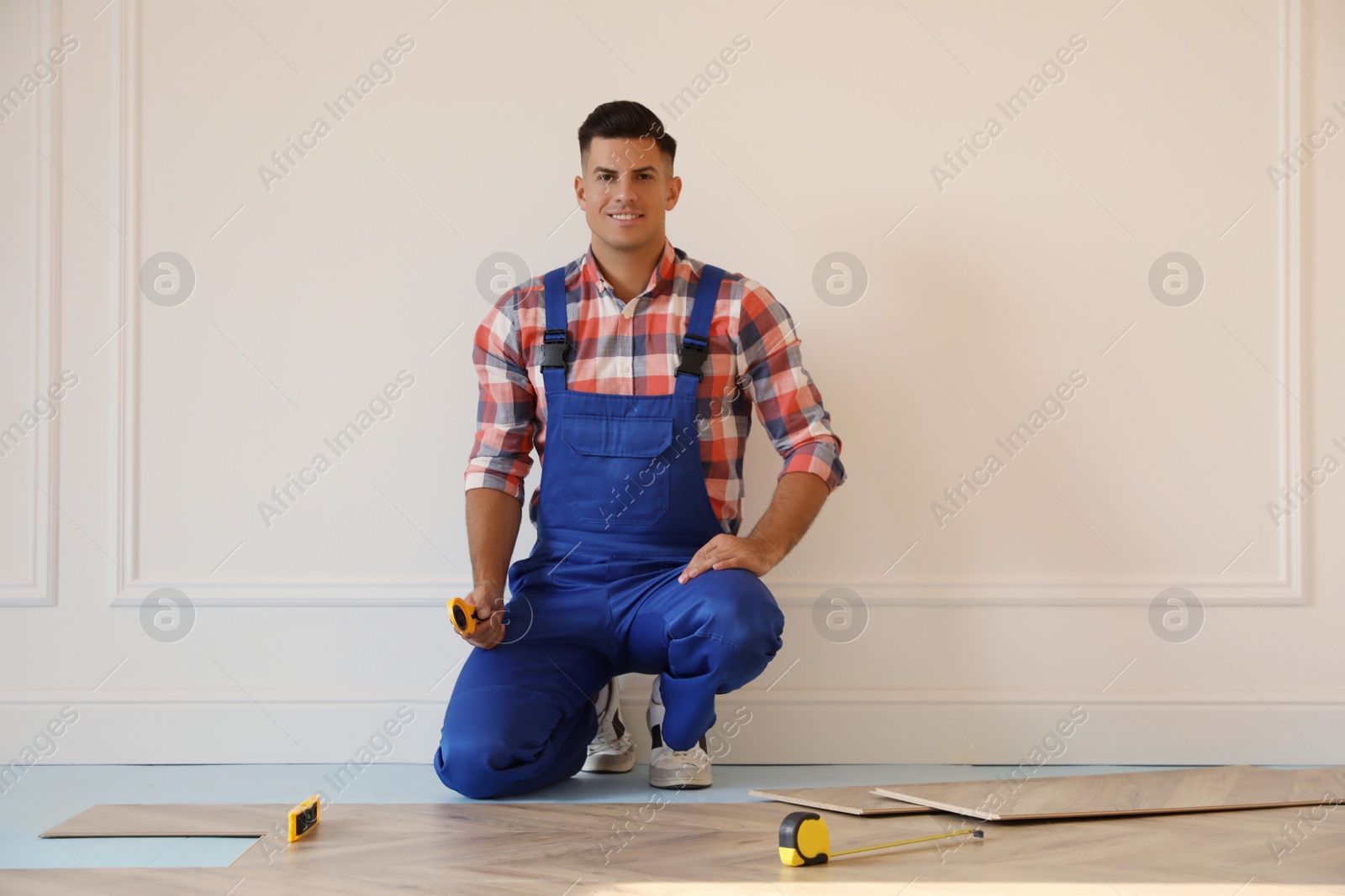 Photo of Professional worker installing new parquet flooring indoors