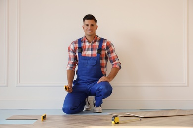 Professional worker installing new parquet flooring indoors