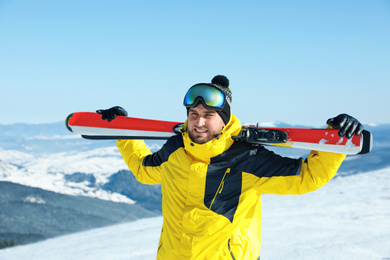 Happy man with ski equipment in mountains. Winter vacation