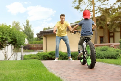 Dad teaching son to ride bicycle outdoors