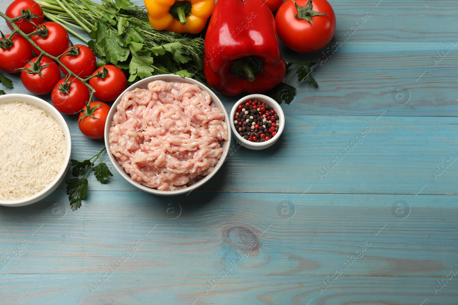 Photo of Making stuffed peppers. Ground meat and other ingredients on light blue wooden table, flat lay. Space for text