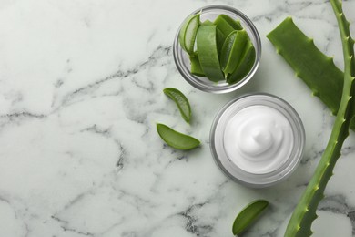 Photo of Jar with cream and cut aloe leaves on white marble table, flat lay. Space for text