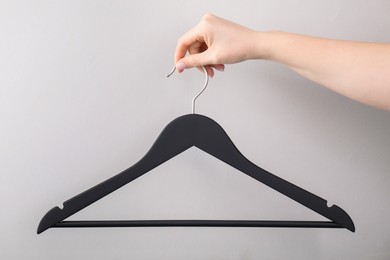 Photo of Woman holding hanger on light grey background, closeup