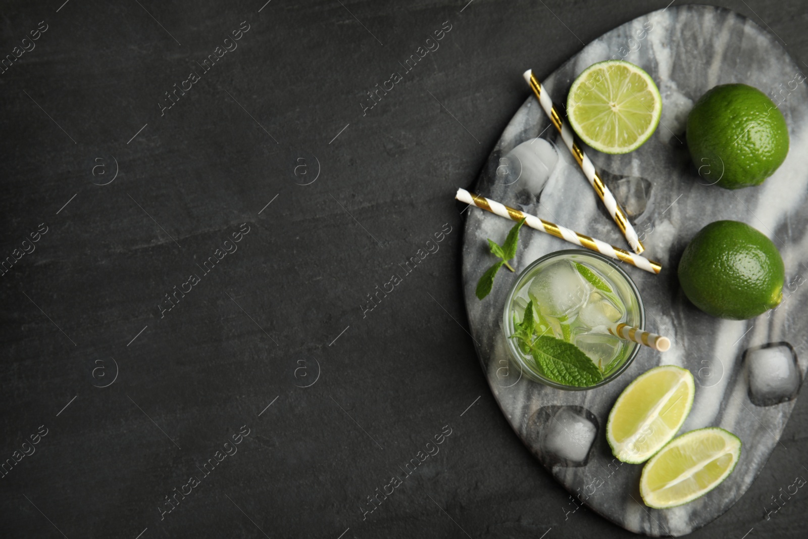Photo of Delicious mojito and ingredients on black table, top view. Space for text