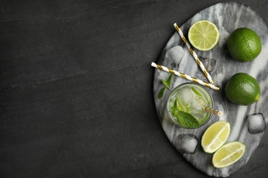 Delicious mojito and ingredients on black table, top view. Space for text