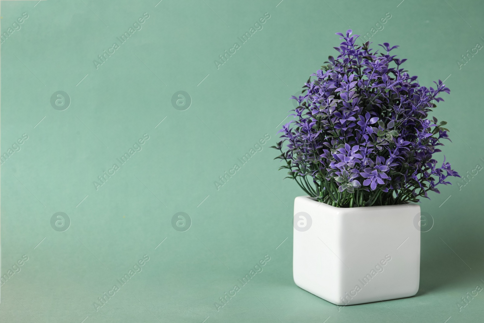 Photo of Beautiful artificial plant in flower pot on color background, space for text
