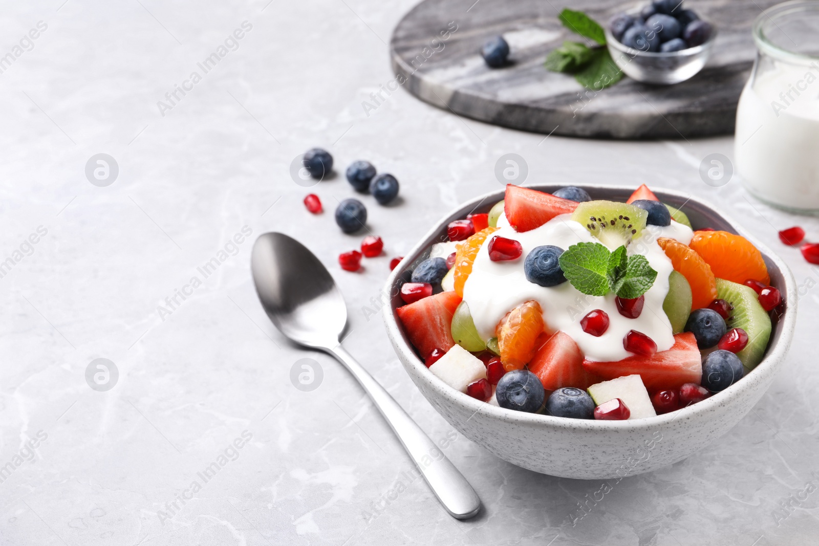 Photo of Delicious fruit salad on grey table. Space for text