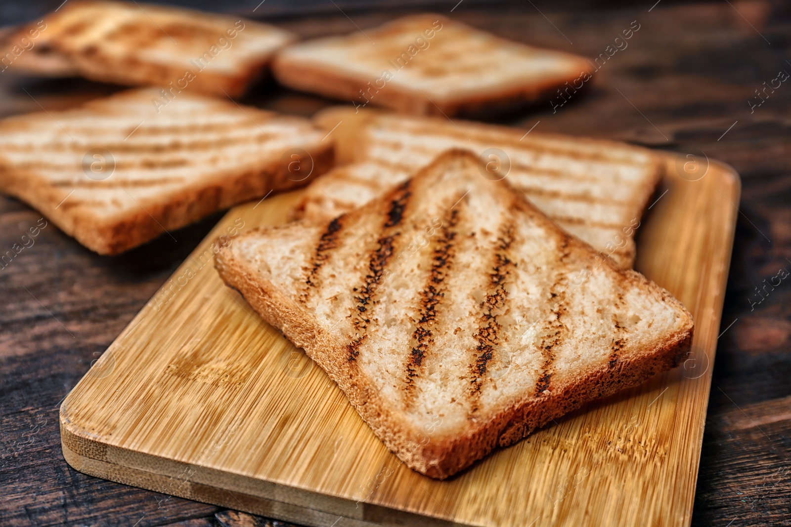 Photo of Tasty toasted bread on wooden board, closeup