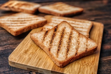 Tasty toasted bread on wooden board, closeup