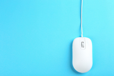 Photo of Modern wired mouse on light blue background, top view. Space for text