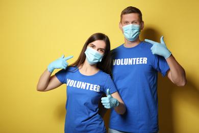 Photo of Volunteers in masks and gloves on yellow background. Protective measures during coronavirus quarantine