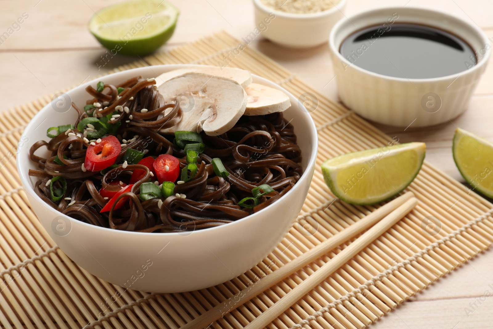 Photo of Tasty buckwheat noodles (soba) with mushrooms, onion and chili pepper served on wooden table, closeup