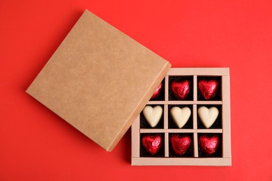 Photo of Tasty heart shaped chocolate candies on red background, flat lay. Happy Valentine's day