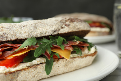 Photo of Delicious sandwich with fresh vegetables and prosciutto on table, closeup view