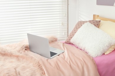 Stylish teenager's room interior with comfortable bed and laptop