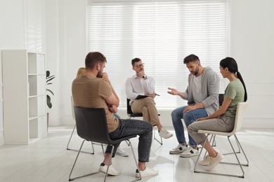 Photo of Psychotherapist working with group of drug addicted people at therapy session indoors