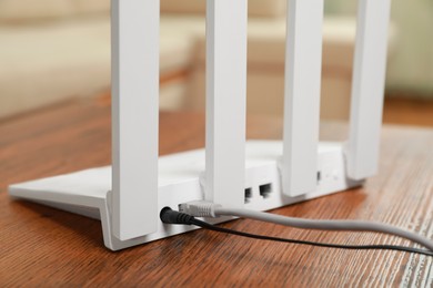 New modern Wi-Fi router on wooden table indoors, closeup