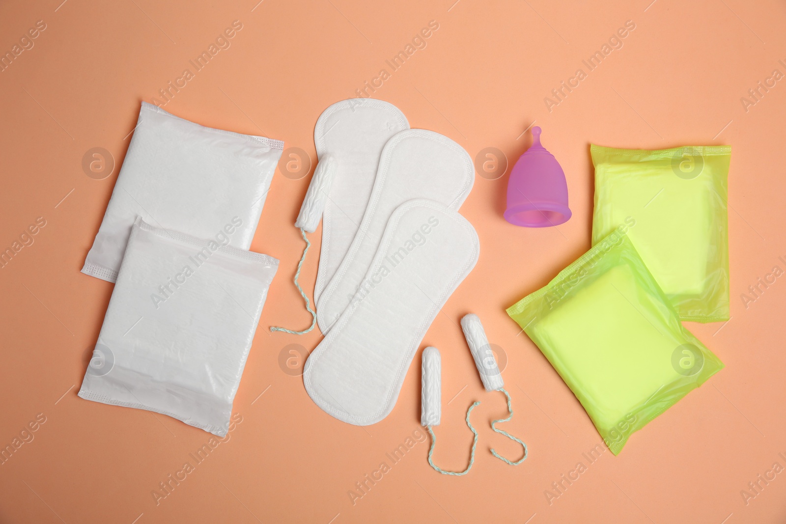 Photo of Menstrual pads and other period products on pale orange background, flat lay