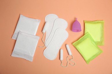 Photo of Menstrual pads and other period products on pale orange background, flat lay