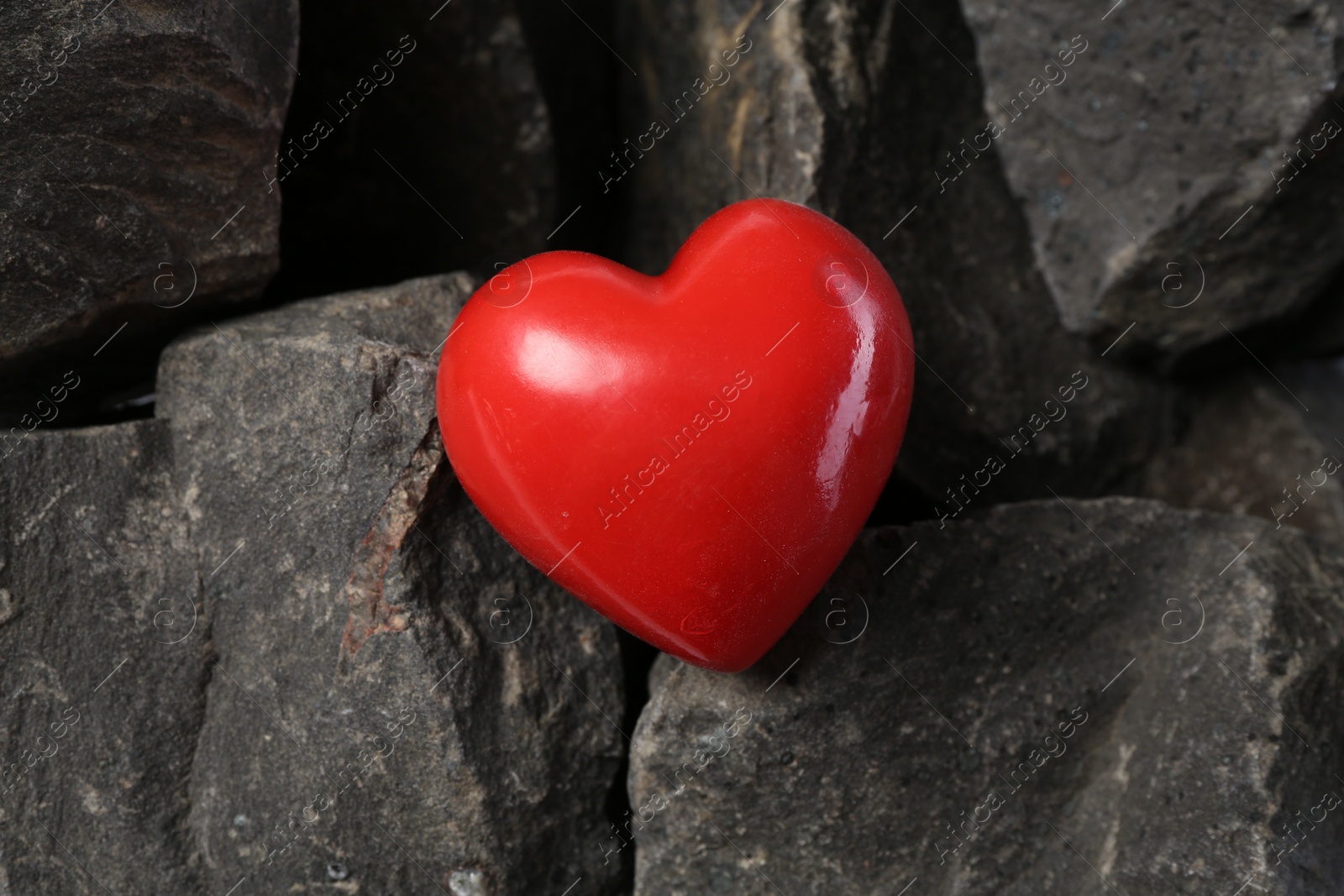 Photo of One red decorative heart on stones, above view