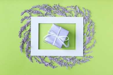 Photo of Frame with painted twigs of plant and gift box on color background, top view