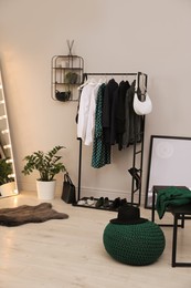 Rack with stylish women's clothes and shoes in dressing room