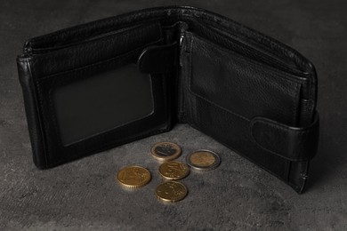 Poverty. Black wallet and coins on grey table