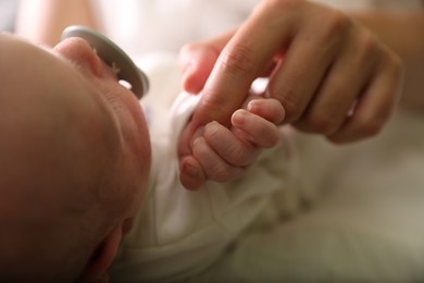 Photo of Mother with newborn baby indoors, focus on hands