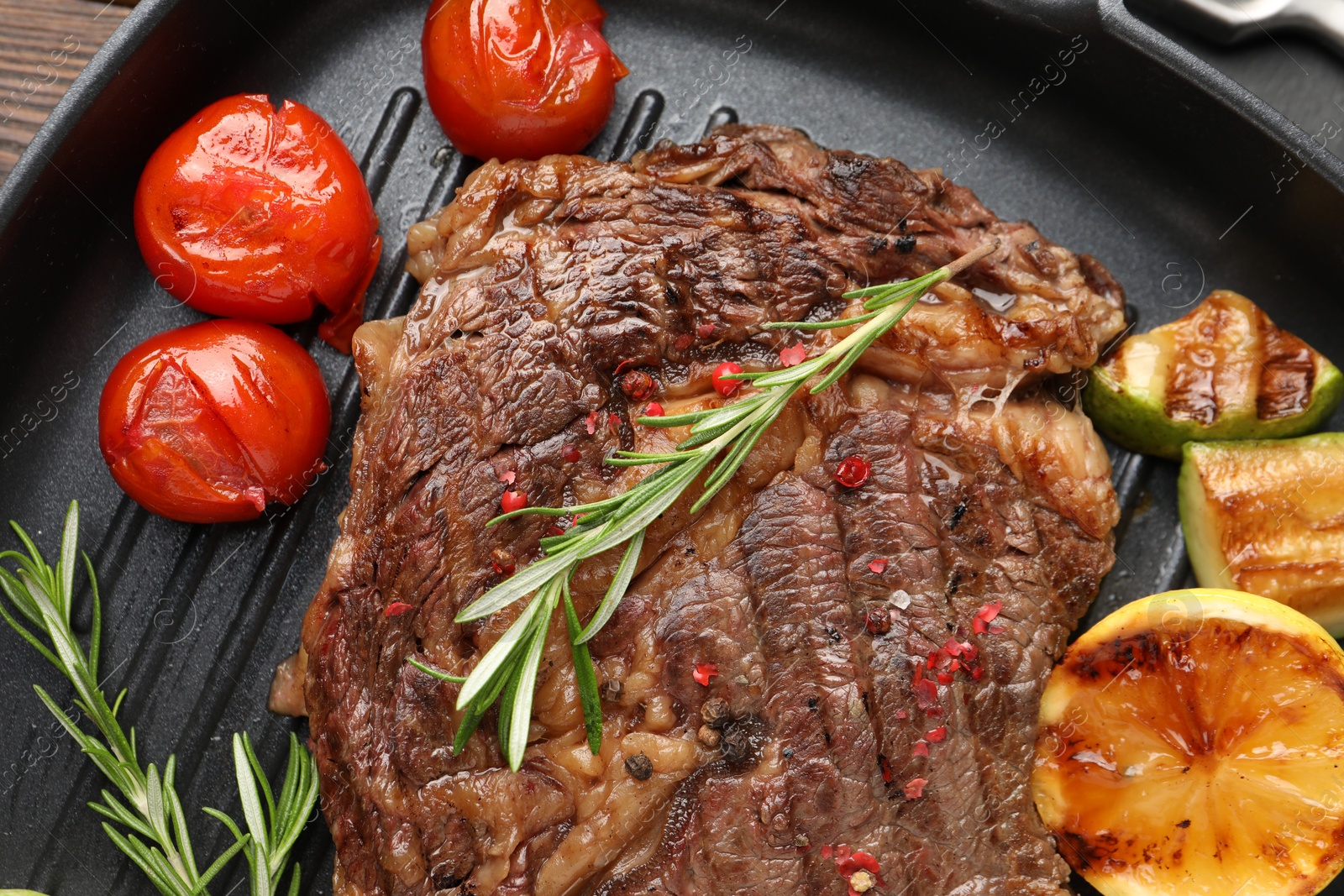 Photo of Delicious grilled beef steak and vegetables in frying pan, top view