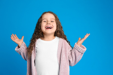 Portrait of cute little girl on light blue background