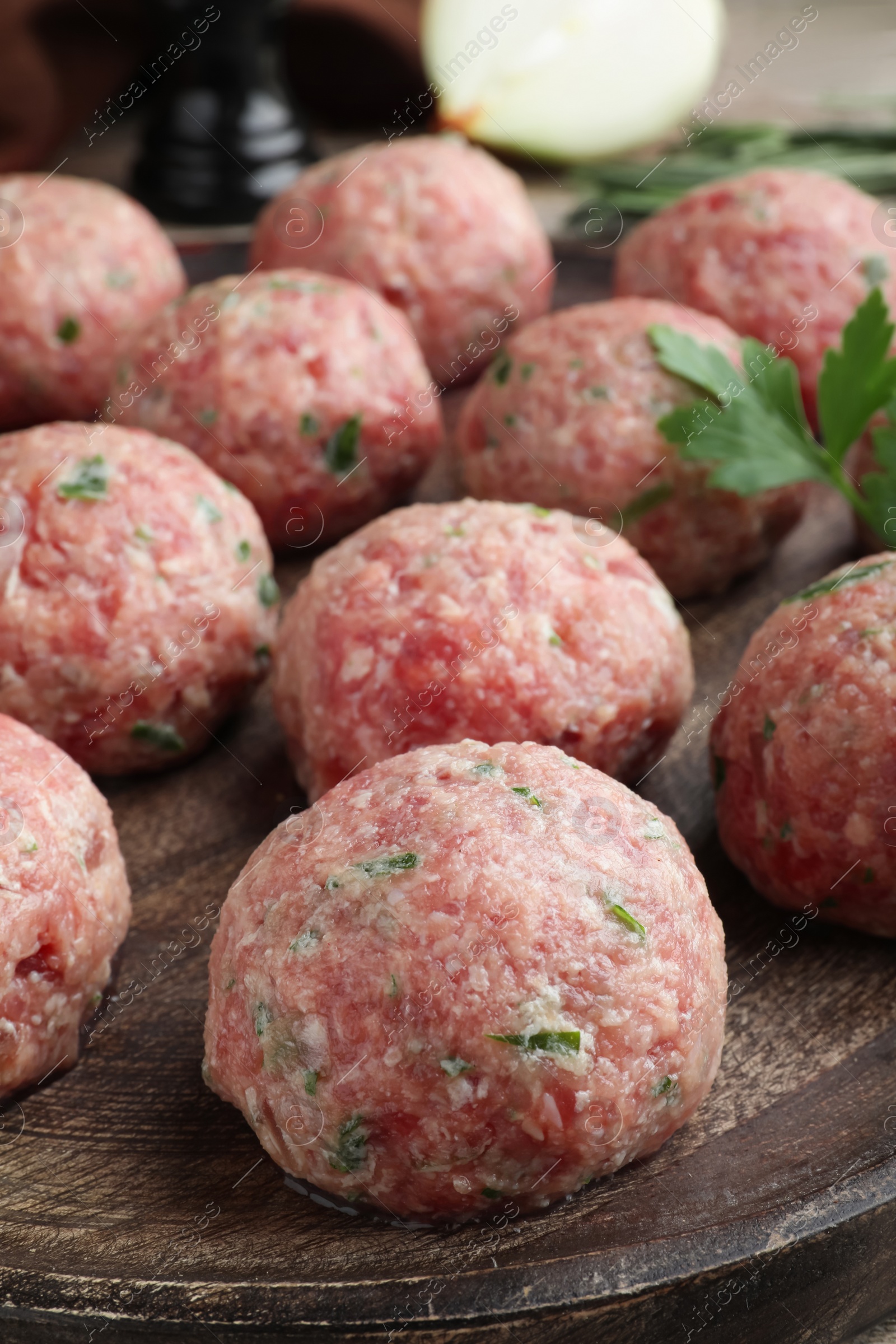 Photo of Many fresh raw meatballs on wooden board, closeup