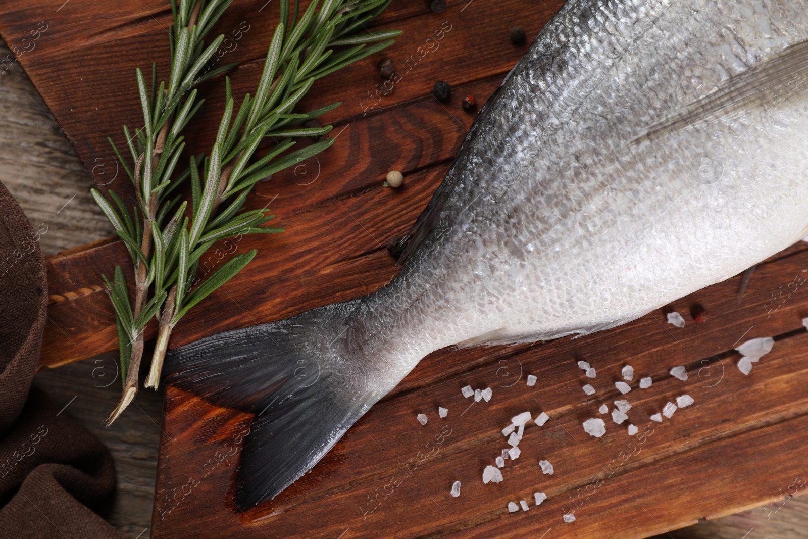 Photo of Raw dorado fish, lemon wedges and spices on wooden table, flat lay