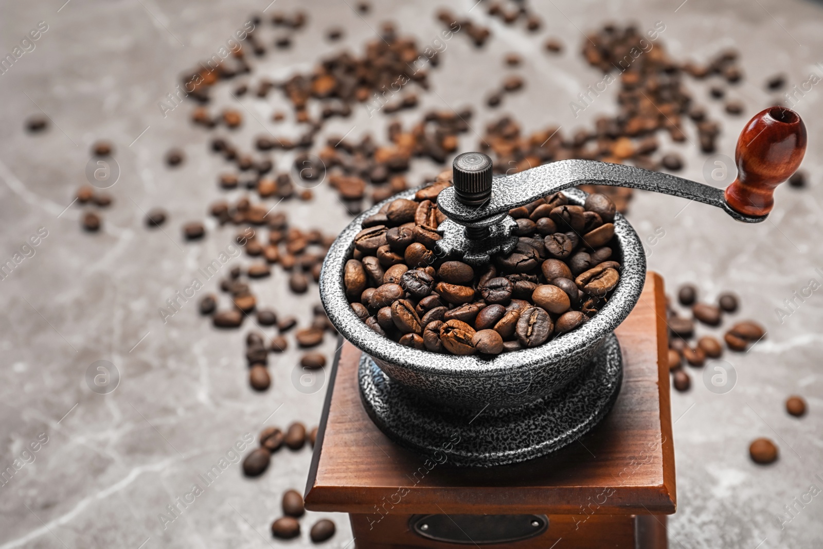 Photo of Coffee grinder with roasted beans on grey background