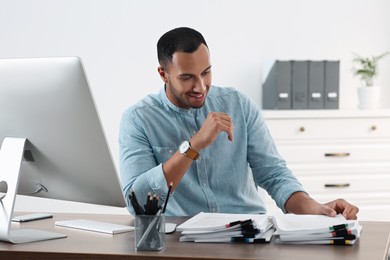 Photo of Happy young businessman working with documents at wooden table in office