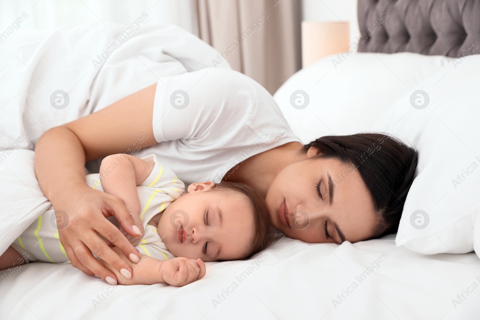 Photo of Mother and her cute baby sleeping on bed indoors