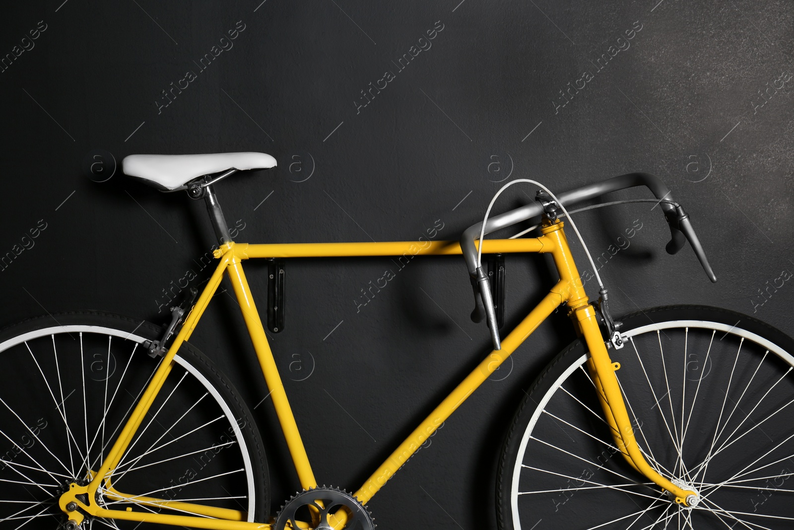Photo of Yellow bicycle hanging on black wall, closeup