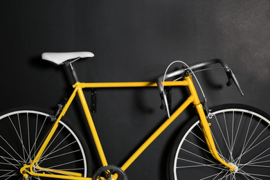Photo of Yellow bicycle hanging on black wall, closeup