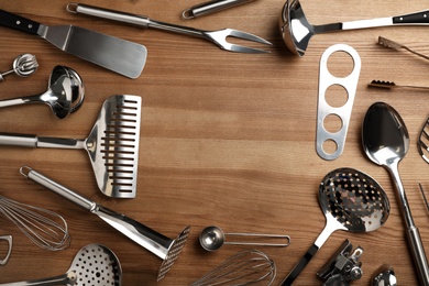 Flat lay composition with different kitchen utensils on wooden background, space for text