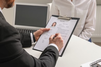 Photo of Human resources manager reading applicant's resume in office, closeup