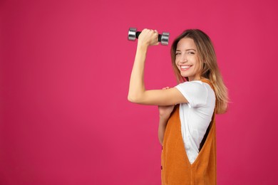 Photo of Woman with dumbbell as symbol of girl power on pink background, space for text. 8 March concept