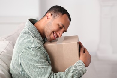 Photo of Happy young man with parcel at home. Internet shopping