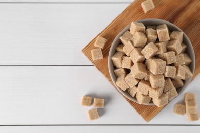 Photo of Brown sugar cubes on white wooden table, flat lay. Space for text